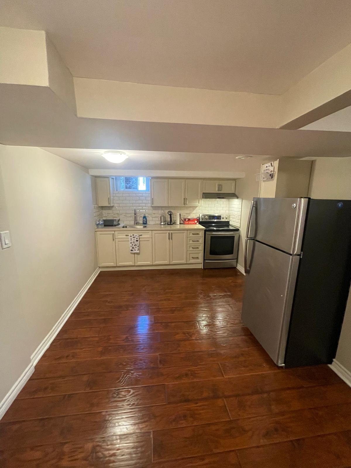 Finished basement with kitchen, white cabinets and dark hardwood floors